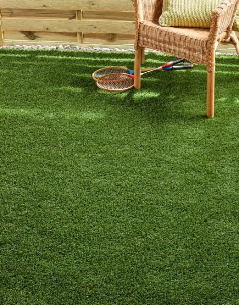 Deck chair and badminton rackets placed on artificial grass.